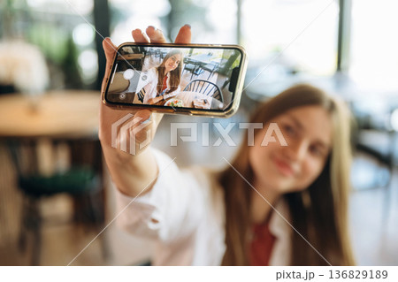 Photo of herself using smartphone. Young woman is in the cafe at daytime 136829189