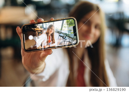 Photo of herself using smartphone. Young woman is in the cafe at daytime 136829190