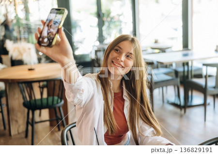 Photo of herself using smartphone. Young woman is in the cafe at daytime 136829191