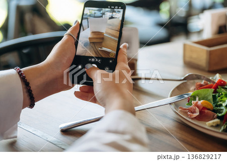 Scanning the QR code by smartphone. Close up view of teenage girl that is sitting in the cafe restaurant 136829217