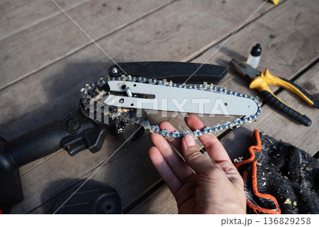 A man repairs an electric saw. Lubrication of the chain. A man repairs an electric saw. Lubrication of the chain. 136829258