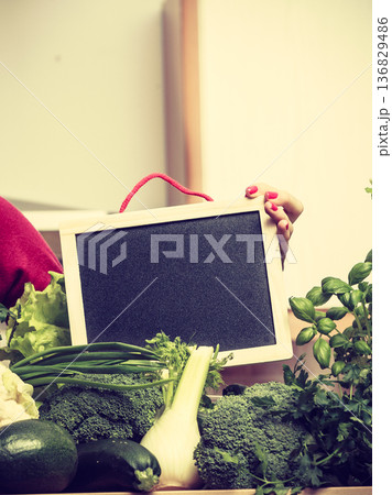 Woman having green vegetables holding board 136829486