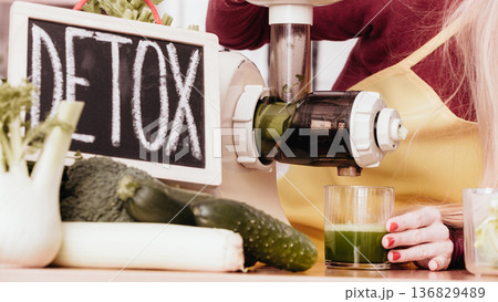 Woman in kitchen making vegetable smoothie juice Woman in kitchen making vegetable smoothie juice 136829489