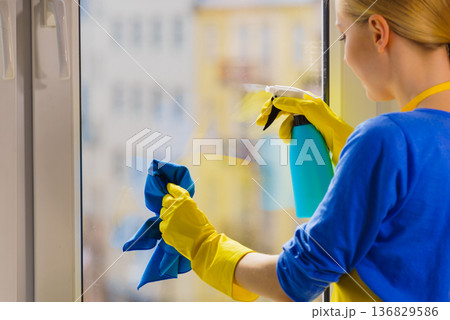Woman cleaning window at home Woman cleaning window at home 136829586