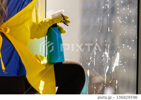 Person spraying window cleaning detergent 136829596