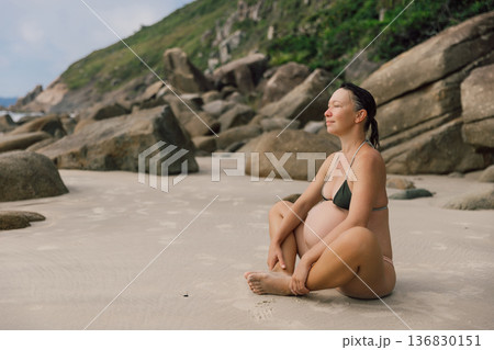 Pregnant woman in swimwear enjoying on ocean beach coastline 136830151