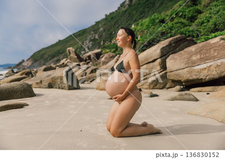 Pregnant smiling woman in swimwear enjoying on beach 136830152