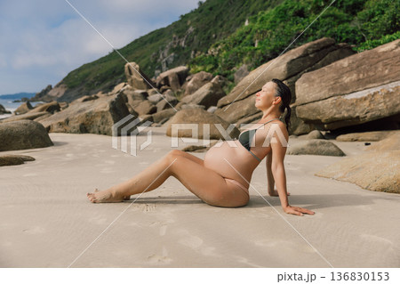 Pregnant young woman in swimwear relaxing on ocean beach 136830153