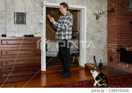 Online surveillance camera for monitoring cat is installed by elderly man in rural house. 136830268