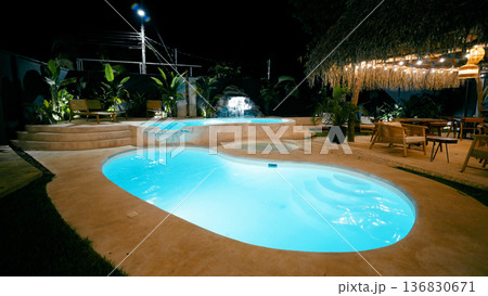 Resort swimming pool area at night with waterfall 136830671