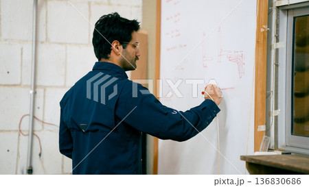 Woodworker drawing carpentry plans on whiteboard 136830686