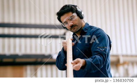 Carpenter inspecting wood plank in workshop Carpenter inspecting wood plank in workshop 136830700