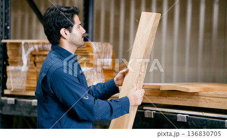 Worker selecting wood plank in carpentry workshop 136830705