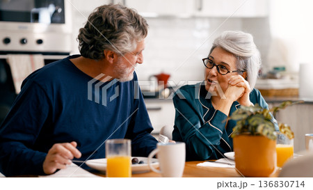 Senior couple enjoying breakfast and conversation in kitchen Senior couple enjoying breakfast and conversation in kitchen 136830714