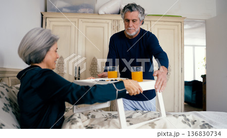 Senior man serving romantic breakfast in bed for woman Senior man serving romantic breakfast in bed for woman 136830734