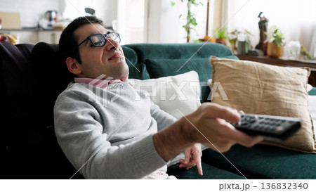 Young man relaxing on sofa watching television Young man relaxing on sofa watching television 136832340