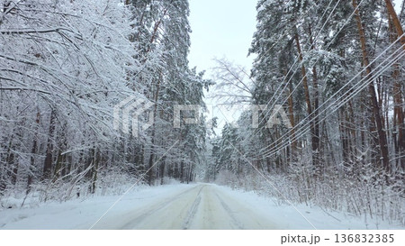 Car driving along snowy forest road in winter landscape 136832385