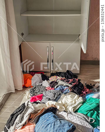 Open Wardrobe with Scattered Clothes on Floor 136832441
