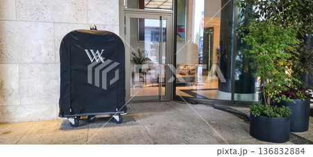 Berlin, Germany - July 17, 2025: Hotel luggage cart with logo parked outside entrance in modern setting Berlin, Germany - July 17, 2025: Hotel luggage cart with logo parked outside entrance in modern setting 136832884