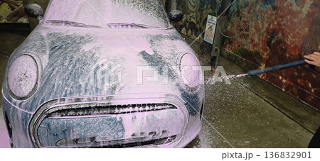 Mini Cooper car being washed with foam in vibrant car wash setting 136832901