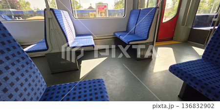 Berlin, Germany - August 27, 2025: Interior of empty train carriage with blue patterned seats and sunlight 136832902