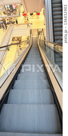 Berlin, Germany - August 27, 2025: Escalator descending in modern shopping mall with bright interior design 136832903