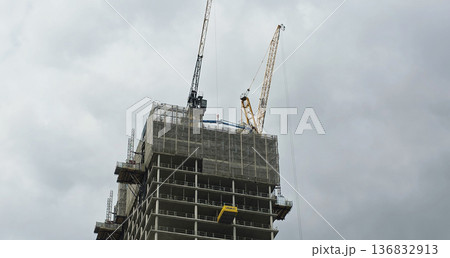 Berlin, Germany - September 17, 2025: Construction site with cranes working on high-rise building under cloudy sky 136832913
