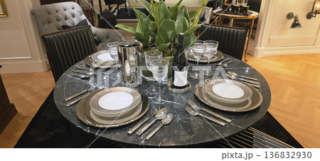 Berlin, Germany - September 19, 2025: Elegant dining table setting with glassware and decorative plant centerpiece 136832930