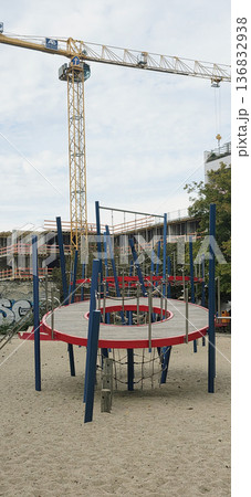 Berlin, Germany - September 25, 2025: Modern playground structure with climbing frame and construction site nearby Berlin, Germany - September 25, 2025: Modern playground structure with climbing frame and construction site nearby 136832938