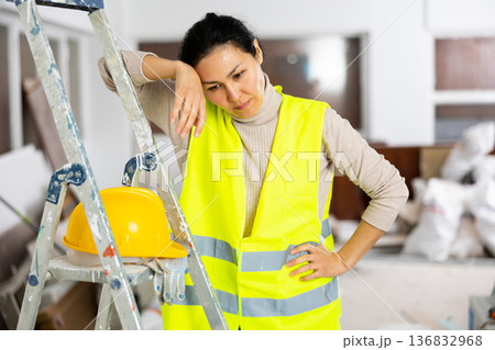 Exhausted woman builder standing in construction site Exhausted woman builder standing in construction site 136832968