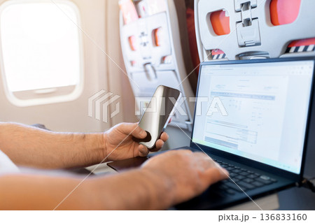 Adult caucasian man using smartphone and laptop on airplane tray table Adult caucasian man using smartphone and laptop on airplane tray table 136833160