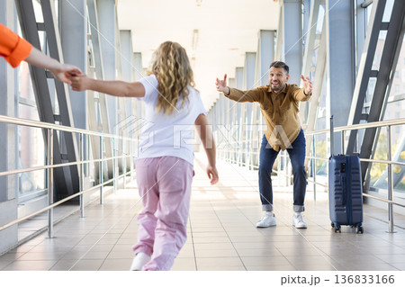 Excited daughter running to father with open arms in airport corridor Excited daughter running to father with open arms in airport corridor 136833166