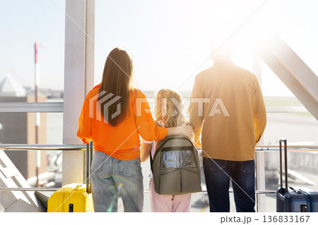 Rear portrait of smiling family at airport terminal, daughter standing between parents Rear portrait of smiling family at airport terminal, daughter standing between parents 136833167