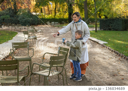 Mother guiding son with camera in sunny autumn city park in Paris Mother guiding son with camera in sunny autumn city park in Paris 136834689