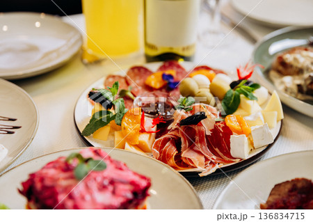 Cheese and meat appetizer platter served on elegant festive restaurant table 136834715