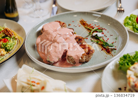 Grilled meat medallions with creamy sauce served on elegant restaurant dinner table 136834719