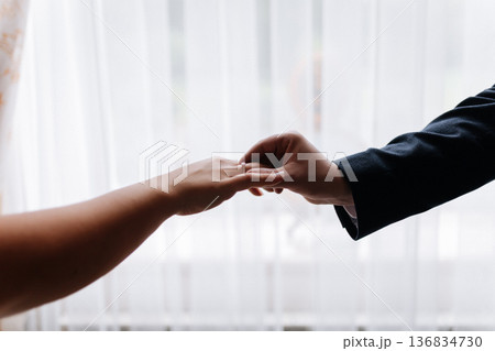 Groom placing wedding ring on brides finger during intimate marriage ceremony moment Groom placing wedding ring on brides finger during intimate marriage ceremony moment 136834730