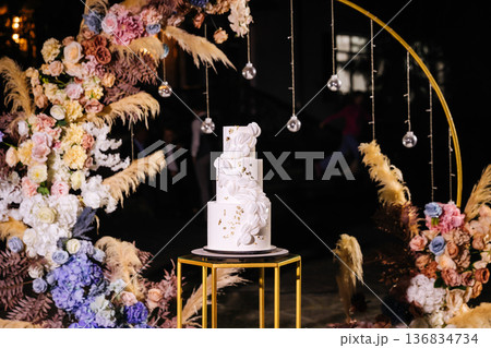 Elegant white wedding cake with floral decor at luxury reception celebration 136834734