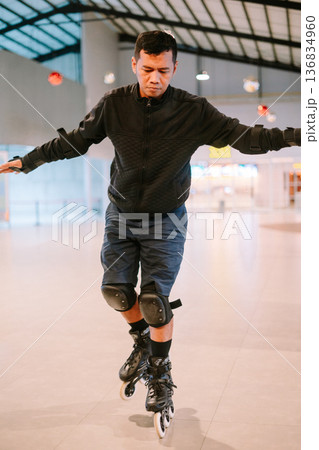 Focused man enjoying inline skating activity indoors Focused man enjoying inline skating activity indoors 136834960