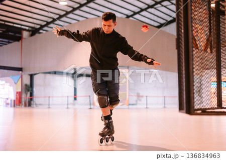 Man practicing balance while inline skating in a large indoor space Man practicing balance while inline skating in a large indoor space 136834963
