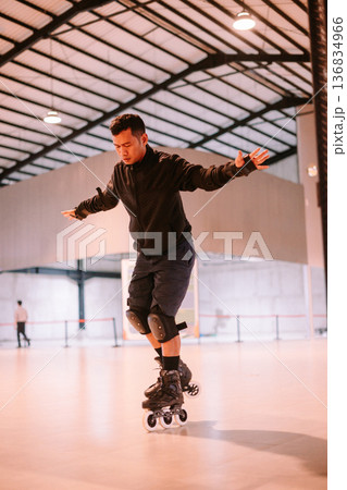 Young Man Concentrating While Rollerblading Indoors Young Man Concentrating While Rollerblading Indoors 136834966