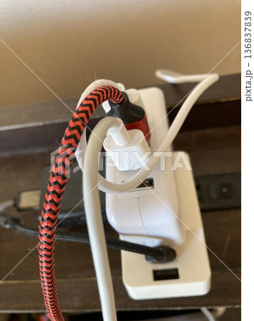 卓上の電源タップに接続された複数のACアダプターとUSBケーブル 136837839