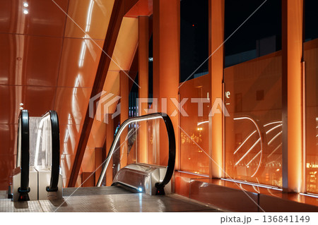 オレンジ照明に包まれたモダン建築空間のエスカレーター（夜景） 136841149