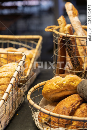 ベーカリーに並ぶ焼きたてパンとバゲットのクローズアップ 暖色照明の店内風景 ベーカリーに並ぶ焼きたてパンとバゲットのクローズアップ 暖色照明の店内風景 136841475