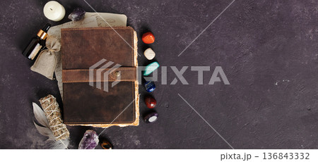 Rustic Leather Journal with Healing Crystals on Dark Background banner 136843332