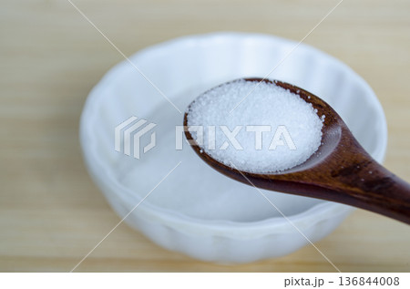 Close up of salt in wooden spoon inside white bowl highlighting seasoning ingredient and controlled sodium consumption. Close up of salt in wooden spoon inside white bowl highlighting seasoning ingredient and controlled sodium consumption. 136844008
