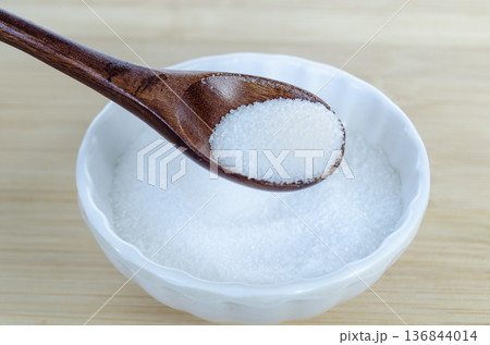 Top view of sugar crystals in wooden spoon symbolizing calorie intake control and healthy nutrition planning. Top view of sugar crystals in wooden spoon symbolizing calorie intake control and healthy nutrition planning. 136844014