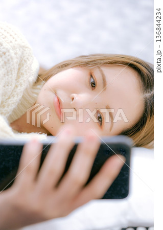 自宅でスマートフォンを見る20代日本人女性 136844234