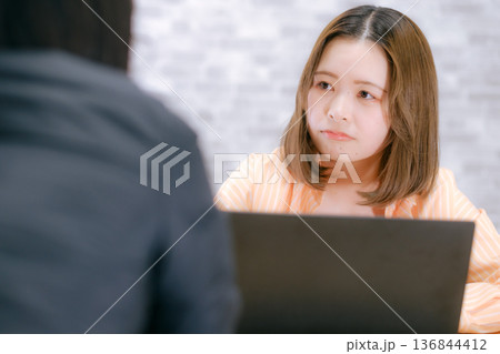 ノートパソコンを前に相談する20代日本人女性 ノートパソコンを前に相談する20代日本人女性 136844412