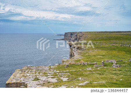 Dramatic coastal cliffs meet the ocean under a cloudy sky in Ireland. 136844457